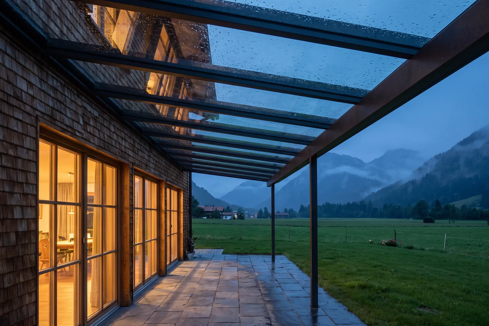 Terrassendach aus Glas an einem Allgäuer Haus in der Dämmerung